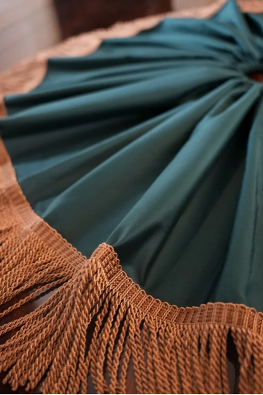 Close-up of the bronze bullion fringe and gathered folds of a forest green cotton sateen tree skirt