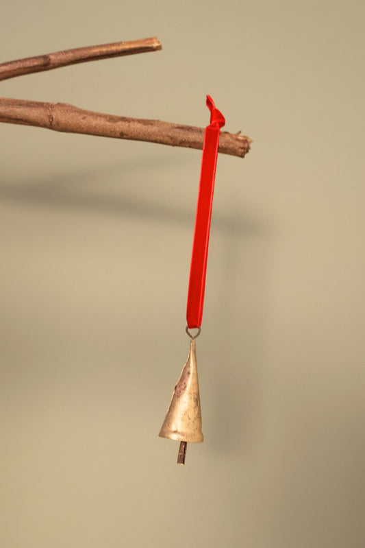 Bijou Rustic Cone Bell in antique gold hanging from a branch on a holly red velvet ribbon