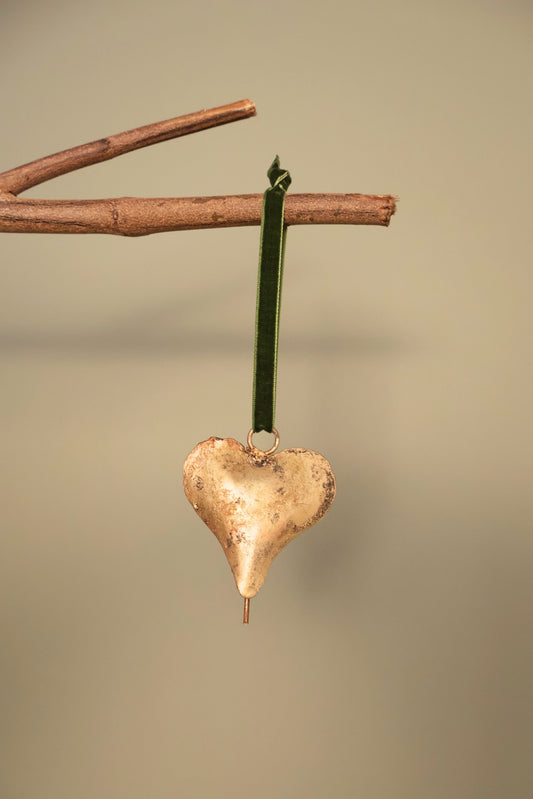 Bijou Rustic Heart Bell in antique gold hanging from a branch on an olive green velvet ribbon