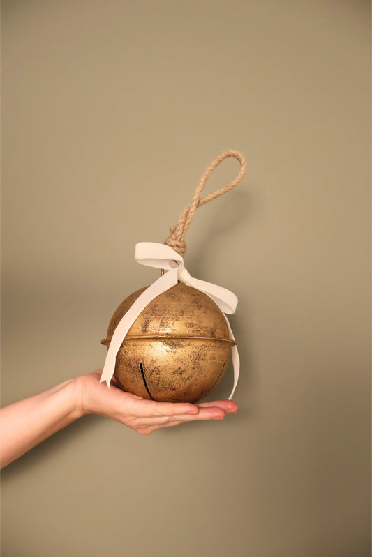 Bijou Rustic Jingle Bell, Large, held in a hand with a cream velvet ribbon bow and natural jute loop