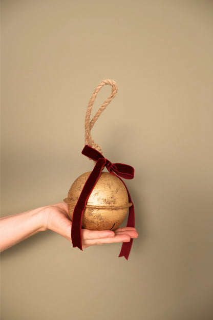 Bijou Rustic Jingle Bell, Medium, held in a hand with a Bordeaux velvet ribbon bow and natural jute loop