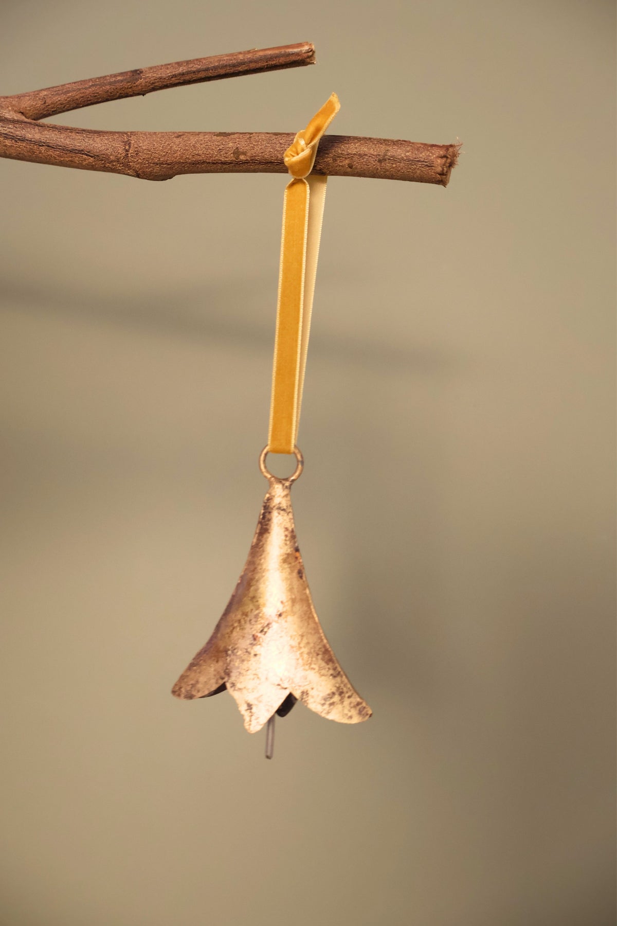 Bijou Rustic Scallop Bell in antique gold hanging from a branch on an antique gold velvet ribbon