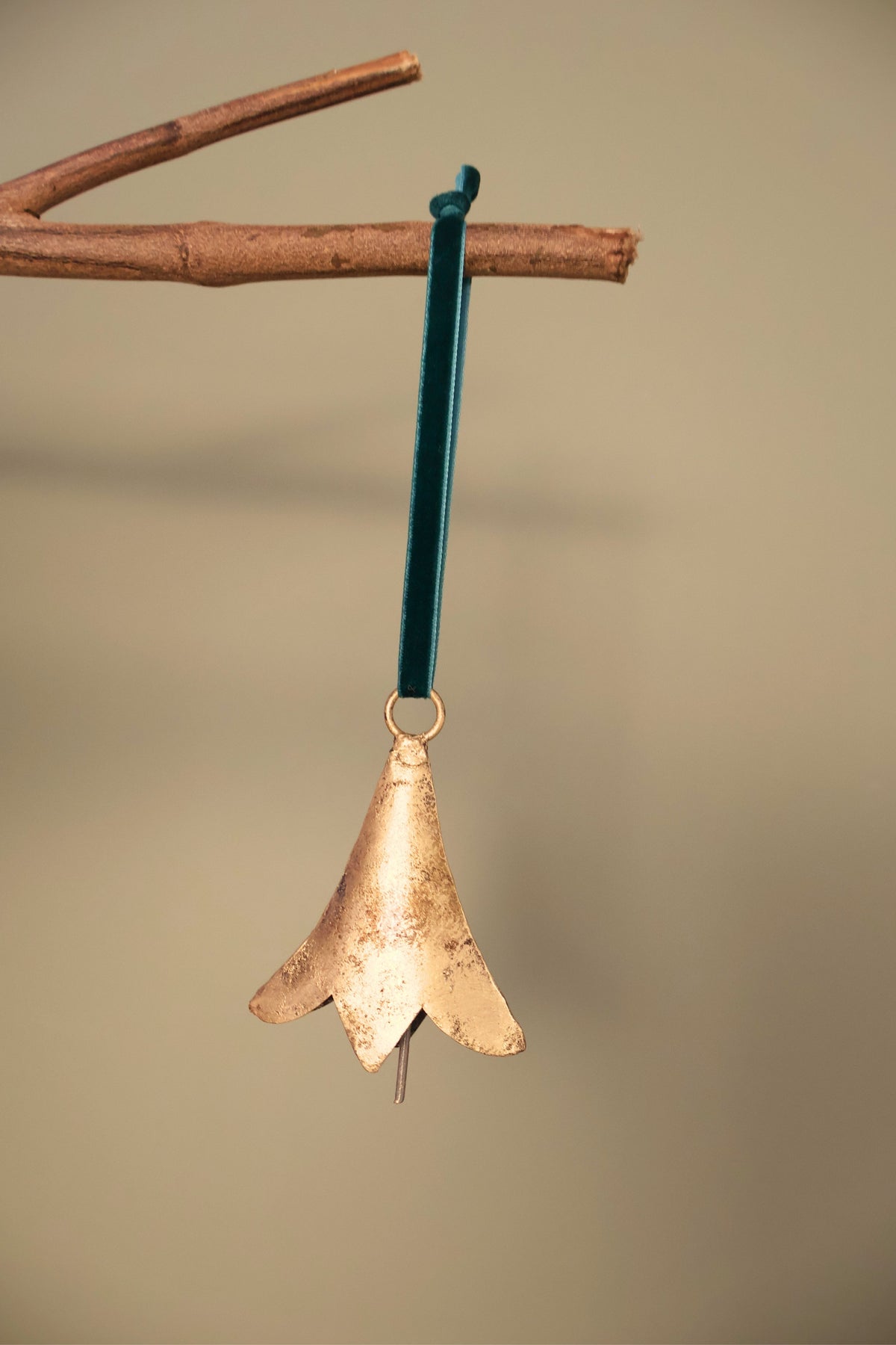 Bijou Rustic Scallop Bell in antique gold hanging from a branch on an emerald green velvet ribbon
