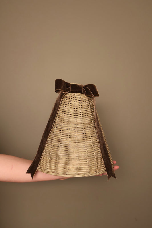 Large Noël rattan bell with a chocolate brown velvet ribbon bow, held in a hand