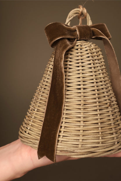 Close-up of a medium Noël rattan bell with a chocolate velvet ribbon bow and long ribbon tails