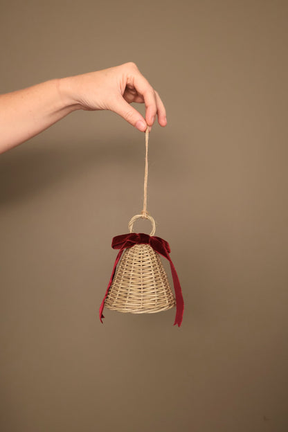 Small Noël rattan bell with a bordeaux velvet ribbon bow, hanging from a jute cord